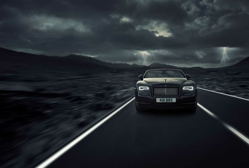 Black Rolls-Royce driving on a highway under a dramatic stormy sky with lightning bolts in the distance.