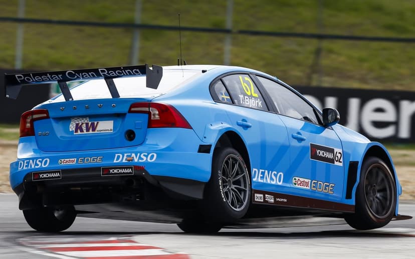 Blue Polestar Volvo S60 race car number 62 lifting a wheel while cornering on a professional racetrack.