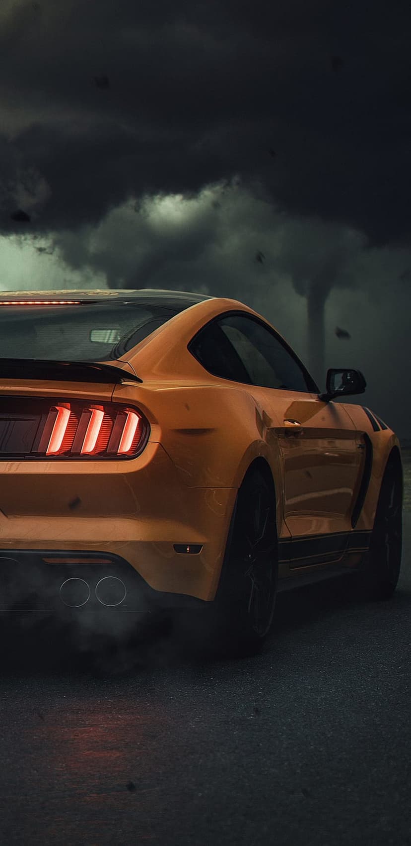 Orange Ford Mustang rear view speeding with glowing taillights and tire smoke under a dark stormy sky.