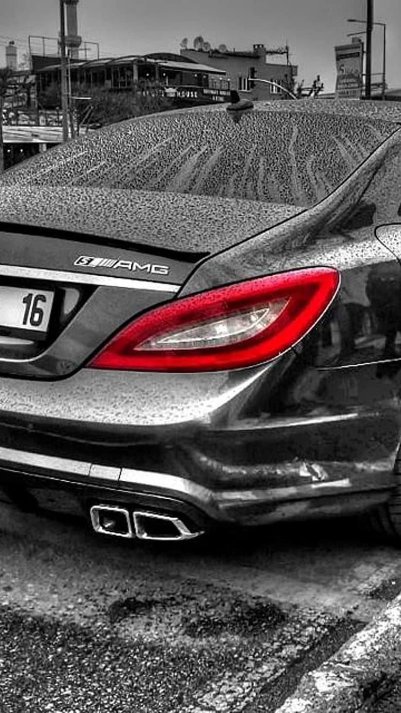 Mercedes-AMG CLS 63 S rear with a glowing red taillight on a rain-slicked road with visible water droplets.