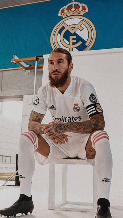 A portrait of a male soccer player sitting in a white uniform
