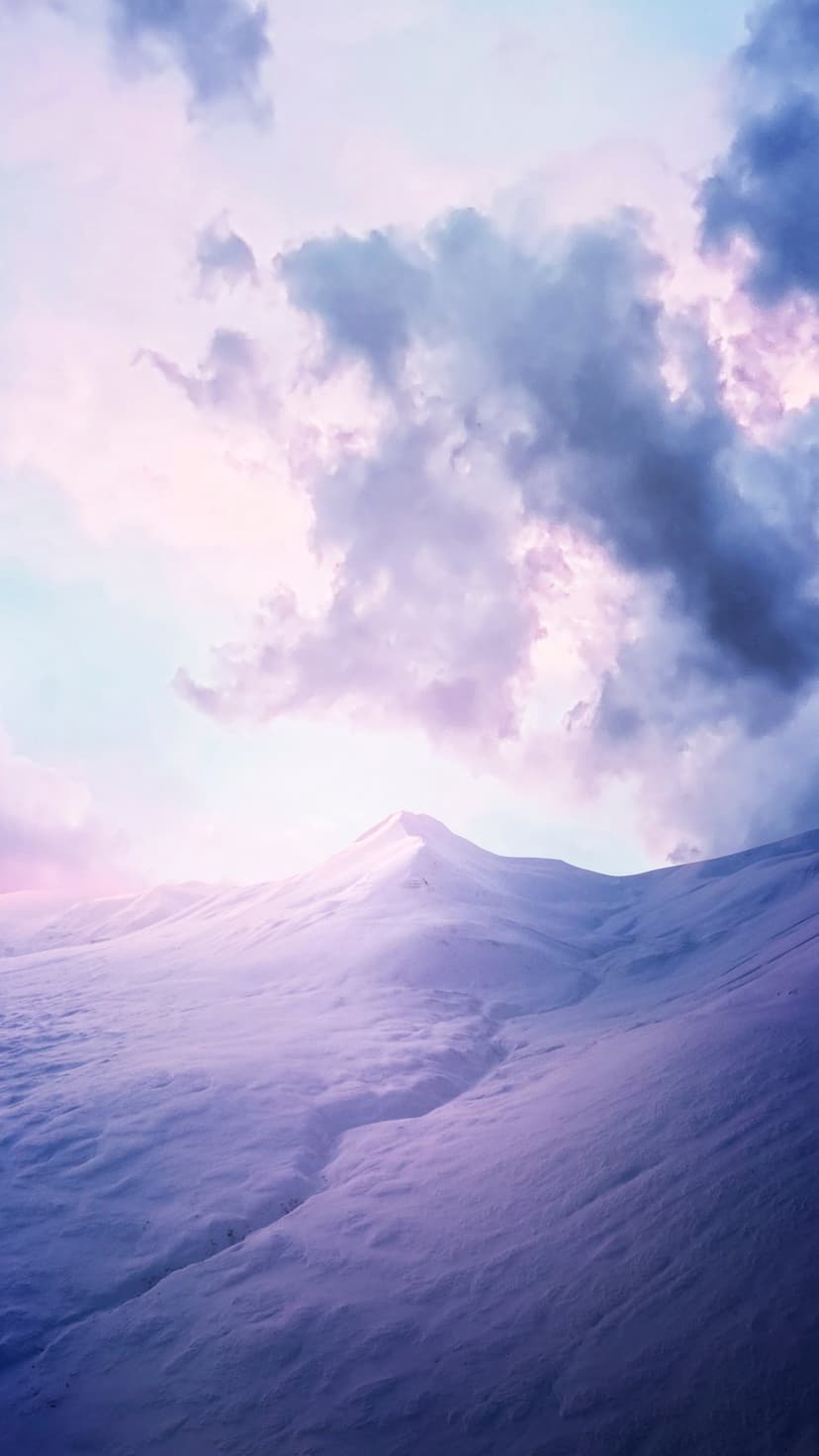 Snowy mountain peaks with a deep central crevice under a purple twilight sky filled with thick dramatic clouds.