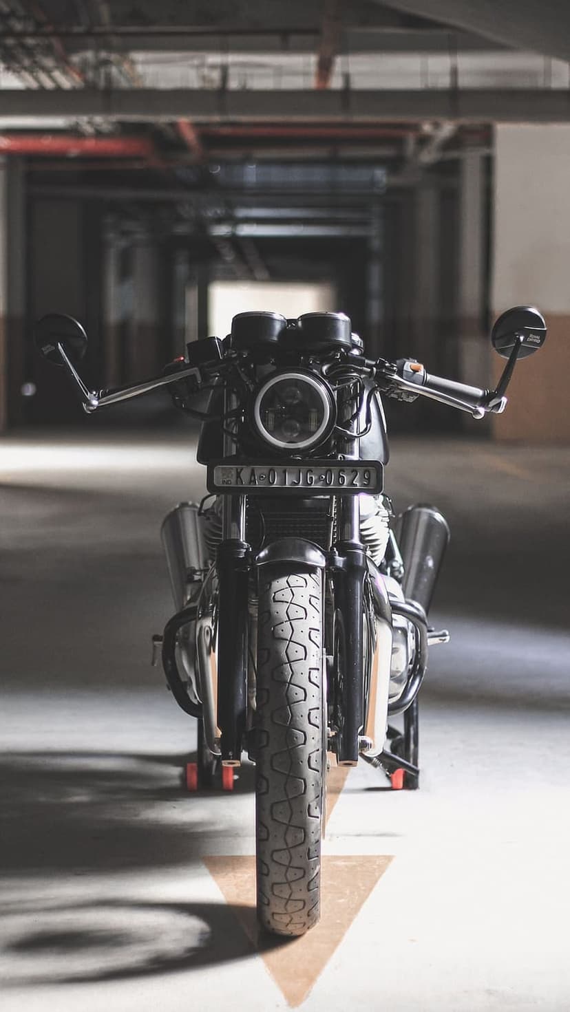 Royal Enfield motorcycle with a round LED headlight and bar-end mirrors parked in a concrete garage.