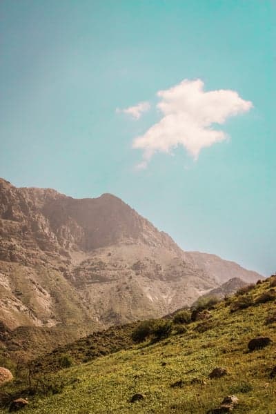 Serene Mountain Landscape with Single Cloud and Green Grassy Slope
