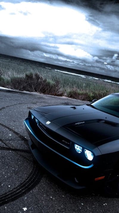 Black Dodge Challenger SRT on Tarmac Under Stormy Skies
