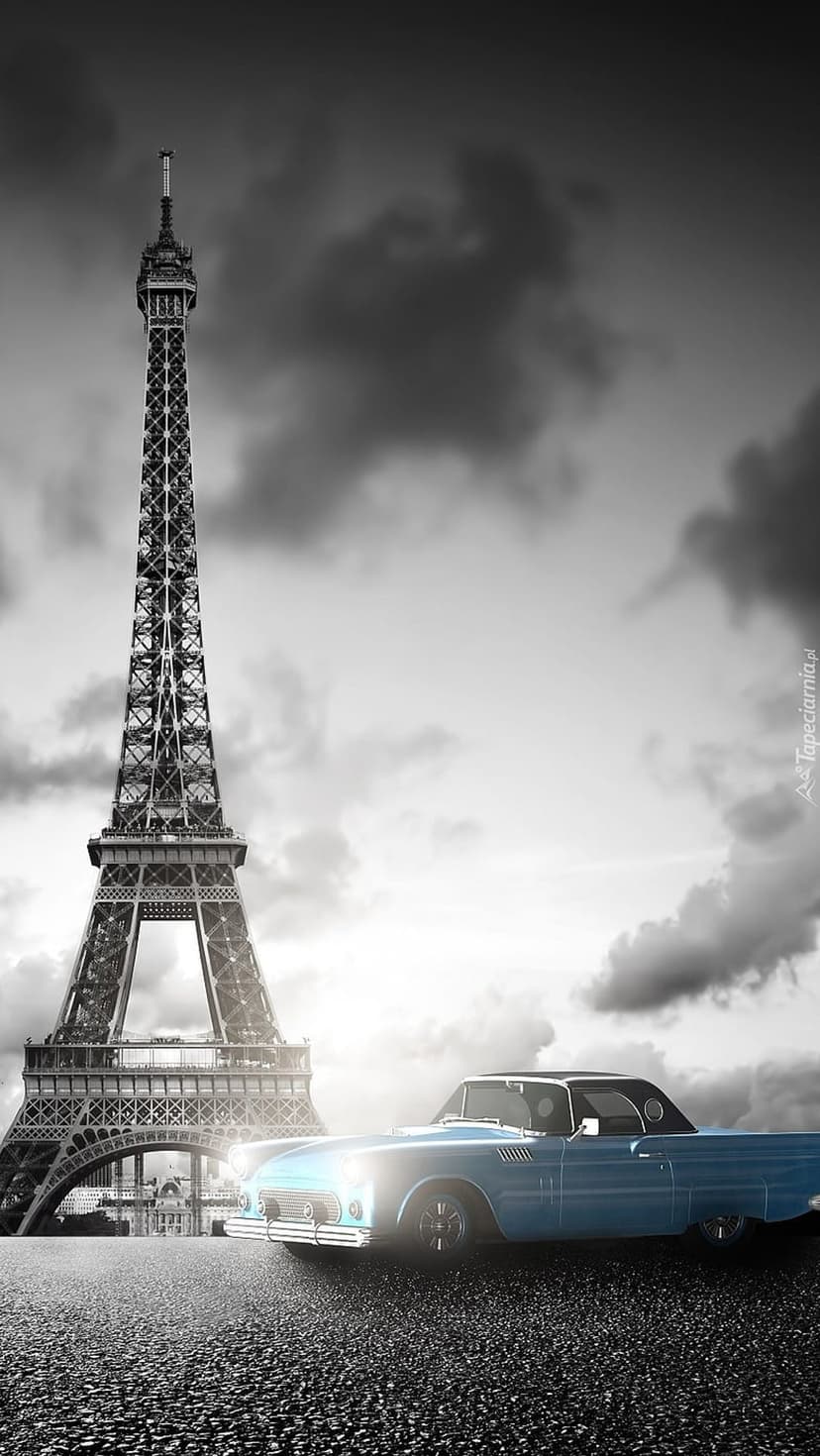 Blue vintage car parked on a Parisian street with the Eiffel Tower and a dramatic cloudy sky in the background.