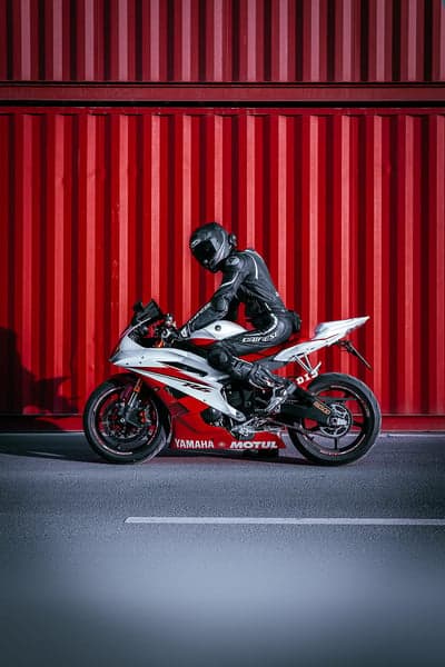 Motorcyclist in Racing Gear Poses on Red Yamaha Bike