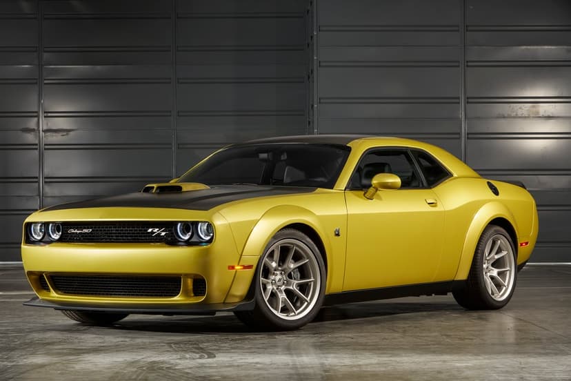 Gold Dodge Challenger Widebody with a black hood parked in a dark industrial studio with soft overhead lighting.