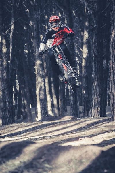 Mountain biker mid-air jump through forest