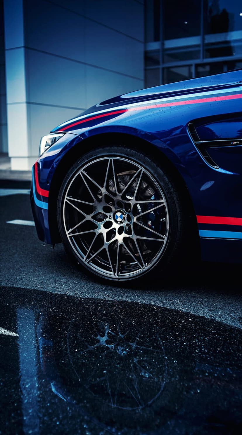 BMW M car alloy wheel and blue bodywork with red and blue stripes reflected on a wet asphalt urban street.