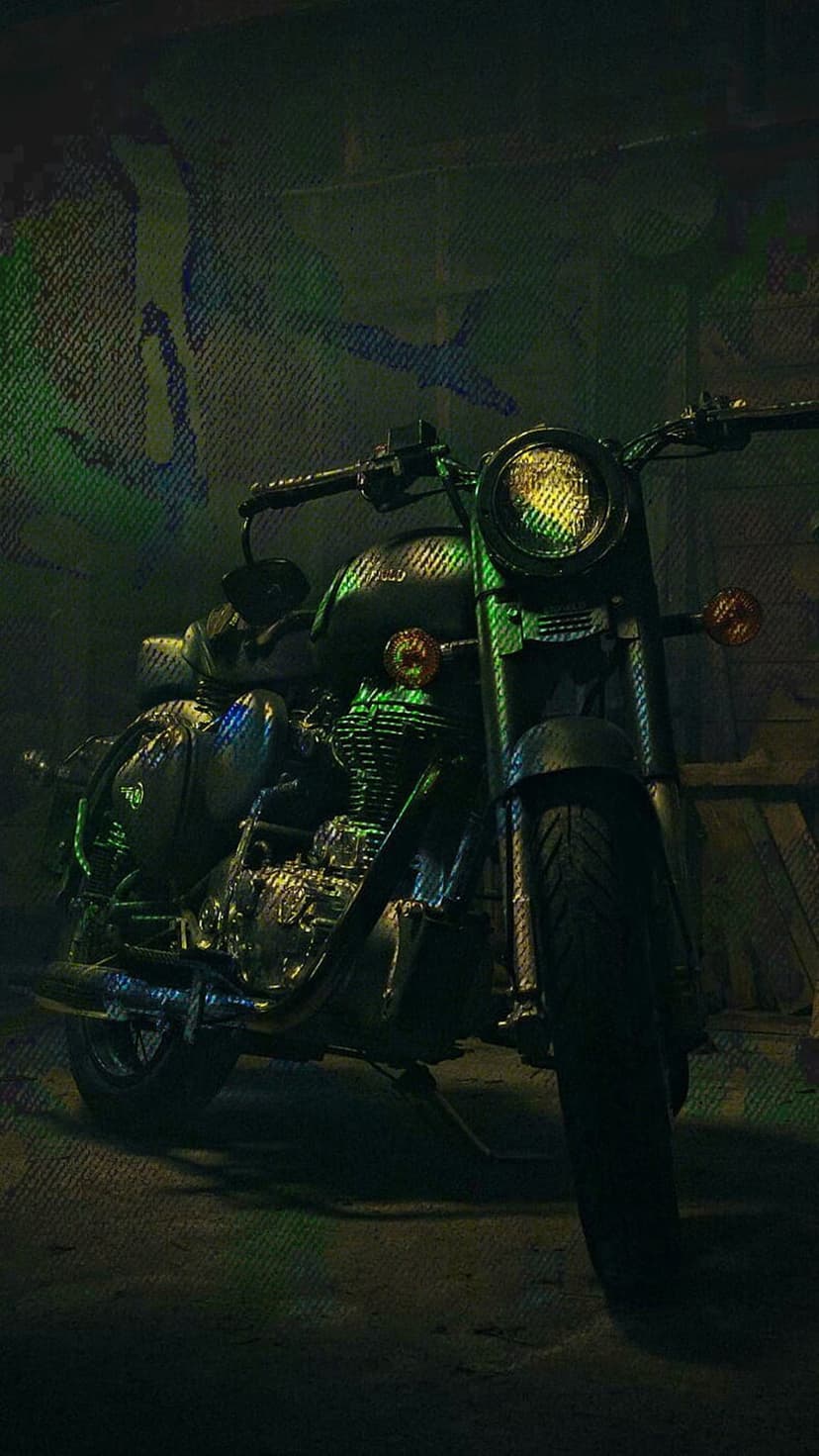 Vintage motorcycle parked in a dark garage with glowing yellow and green lights reflecting on chrome surfaces.