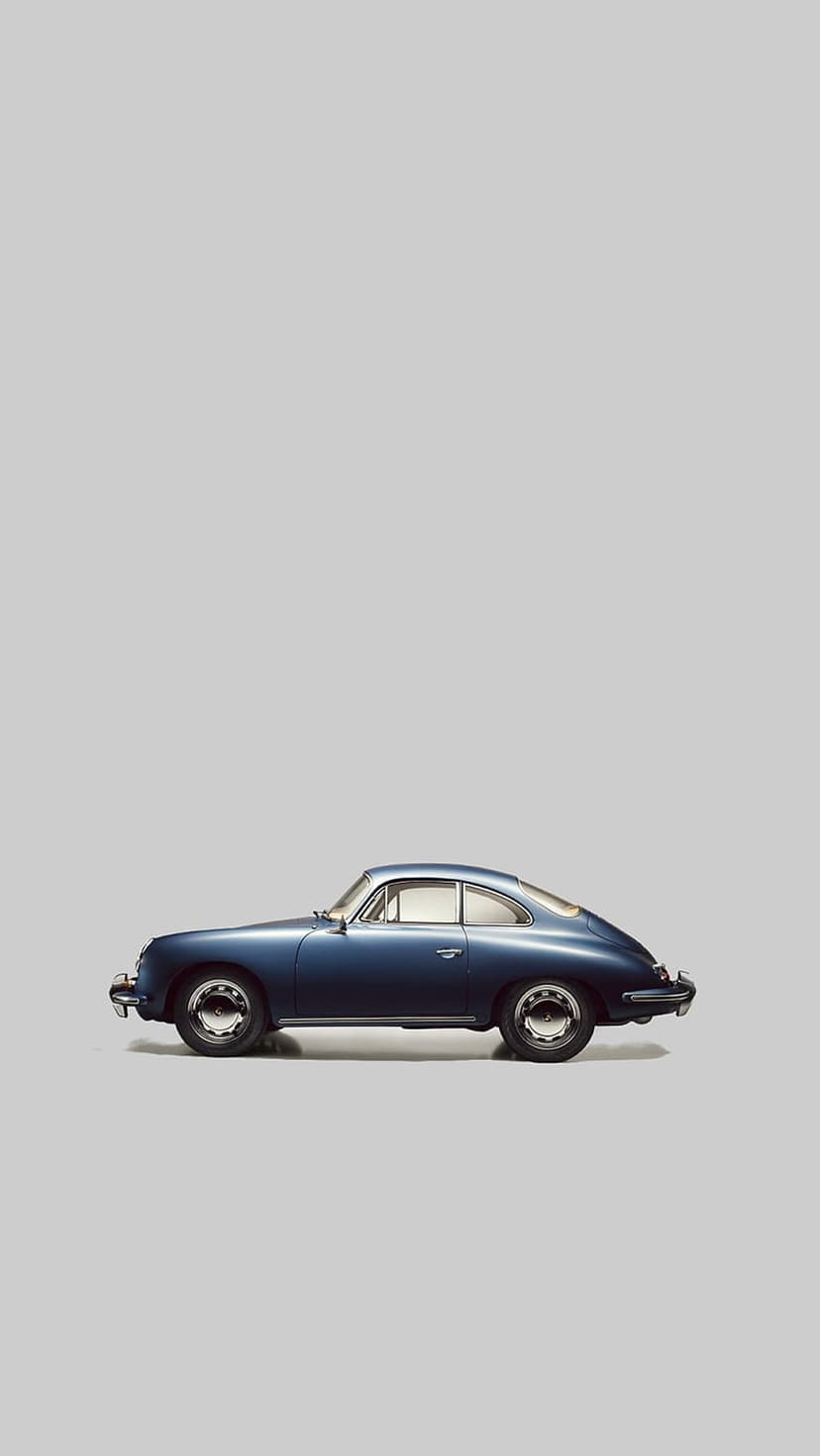 Blue Porsche 356 coupe shows a side profile against a gray backdrop with polished chrome wheels and bumpers.