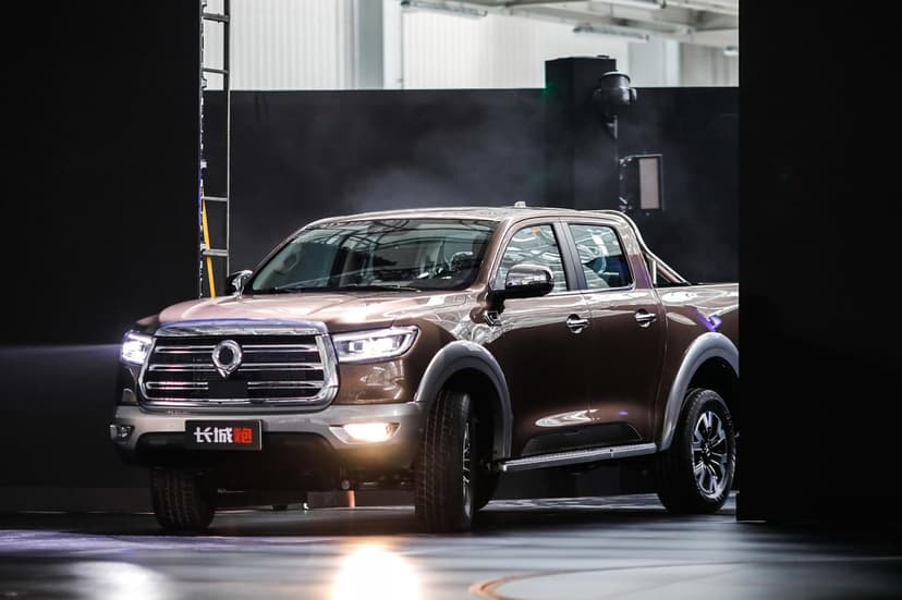 Metallic brown pickup truck on a dark stage with glowing LED headlights and smoke in the background.