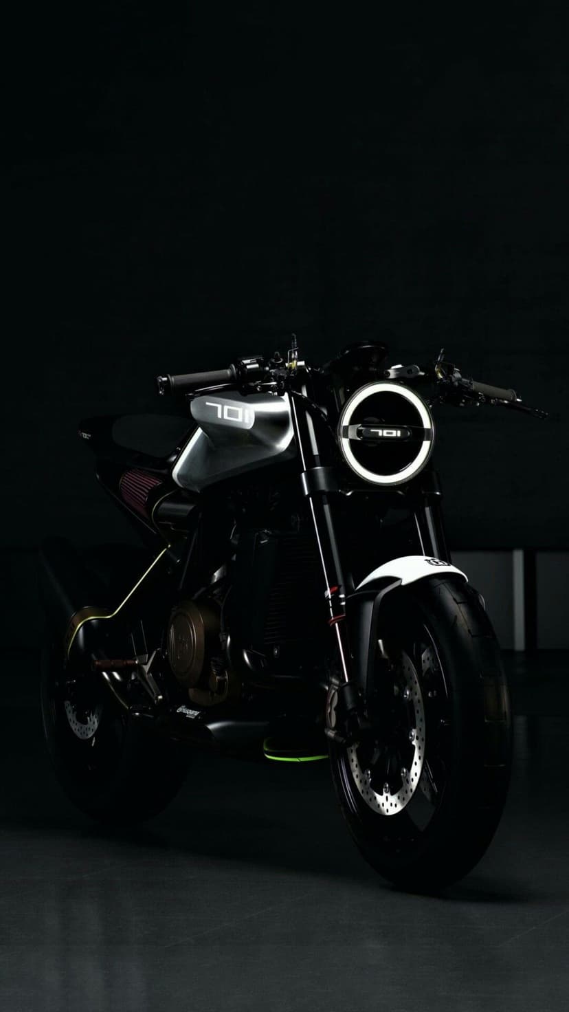 Husqvarna 701 motorcycle with a round LED headlight and exposed engine parts set against a black studio backdrop.