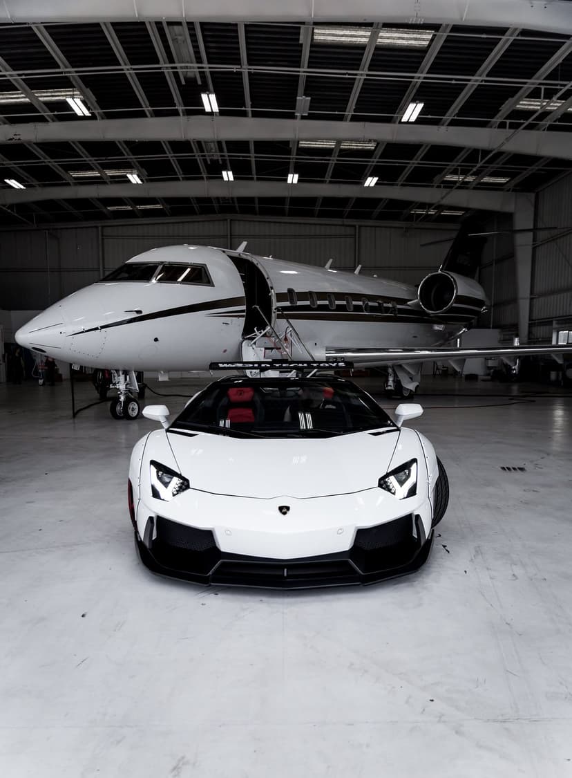 White supercar and private jet parked inside a modern hangar with polished floors and minimalist architecture.