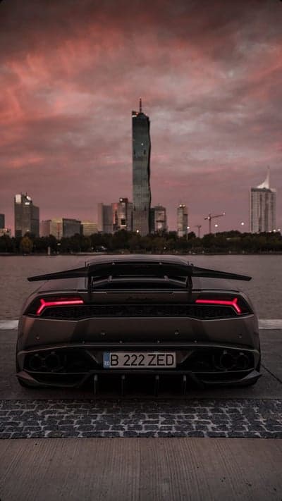 Lamborghini rear view with city skyline at sunset
