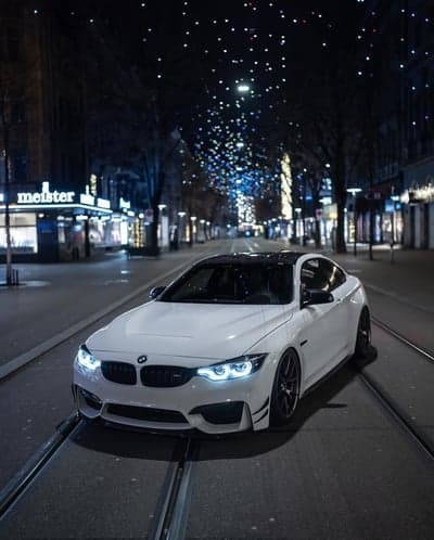 White BMW M4 night drive through city lights