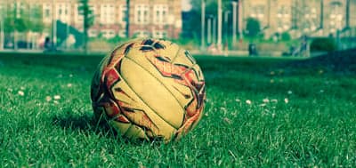 Soccer ball on grass with blurred cityscape background