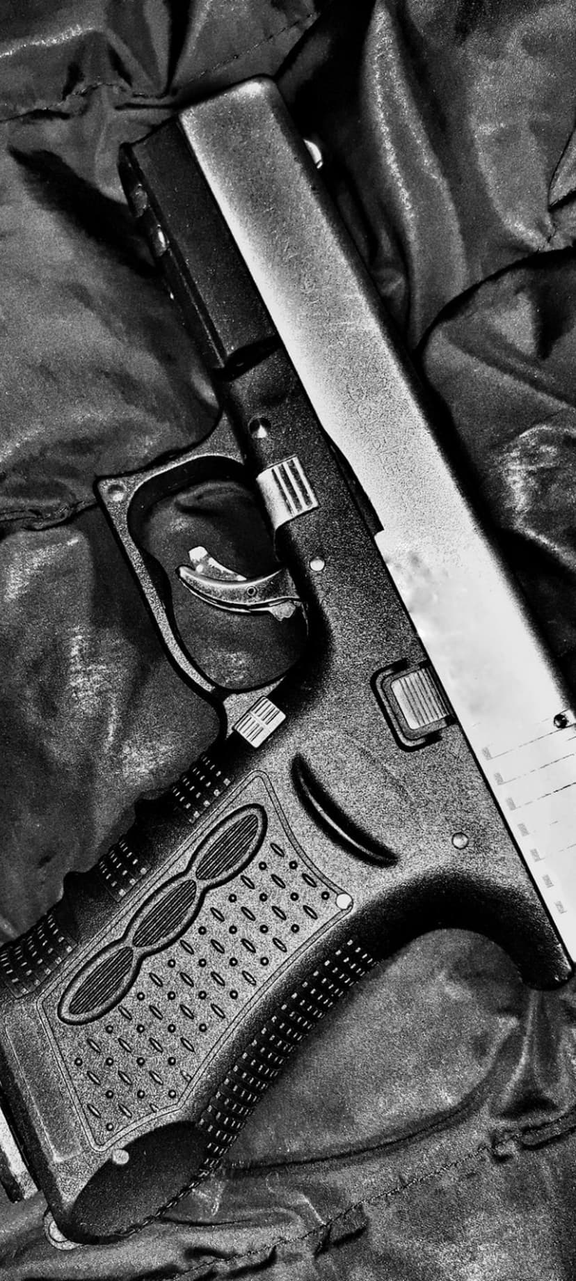 Handgun grip featuring repeating oval stippling next to a smooth metal slide in a monochrome studio setting.