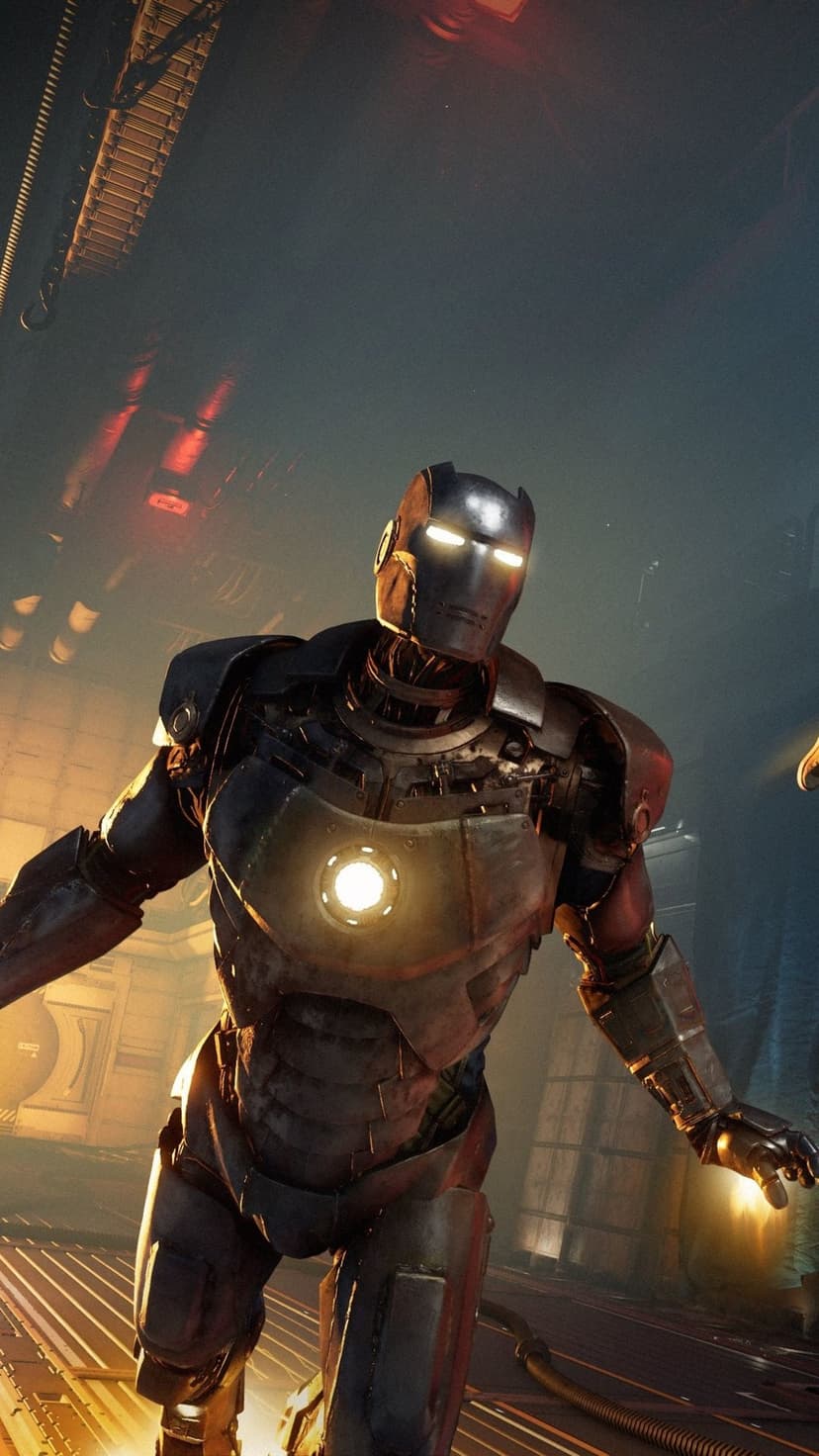 Iron Man prototype suit with glowing blue arc reactor and eyes standing in a dark industrial workshop.