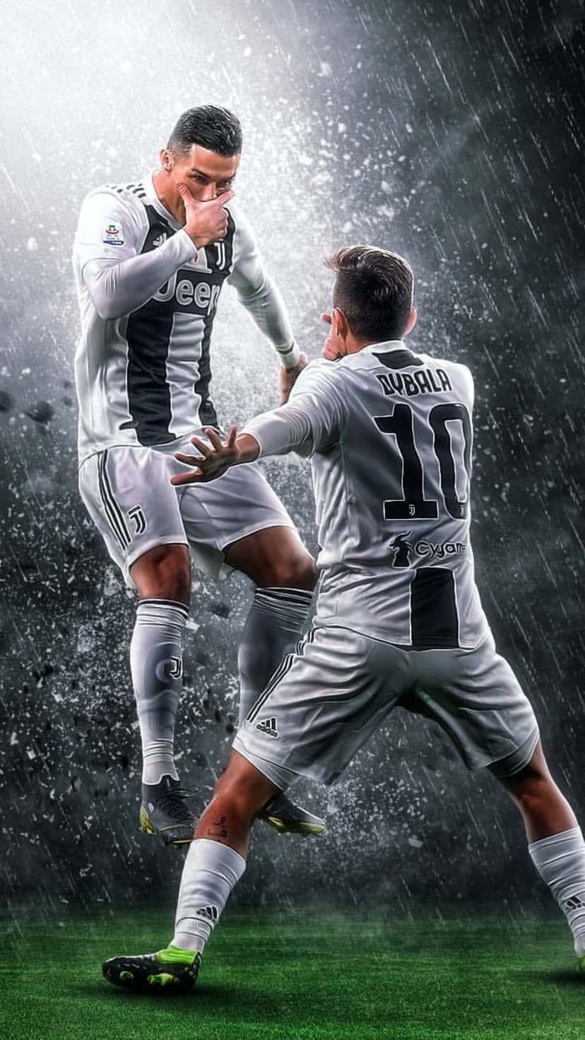 Cristiano Ronaldo and Paulo Dybala embrace in black and white kits during a rainy football match celebration.