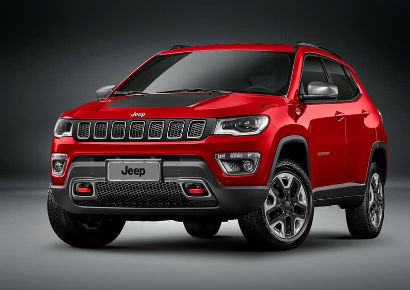 Front view of a red Jeep Compass Trailhawk with black hood decal and red tow hooks in a dark studio.