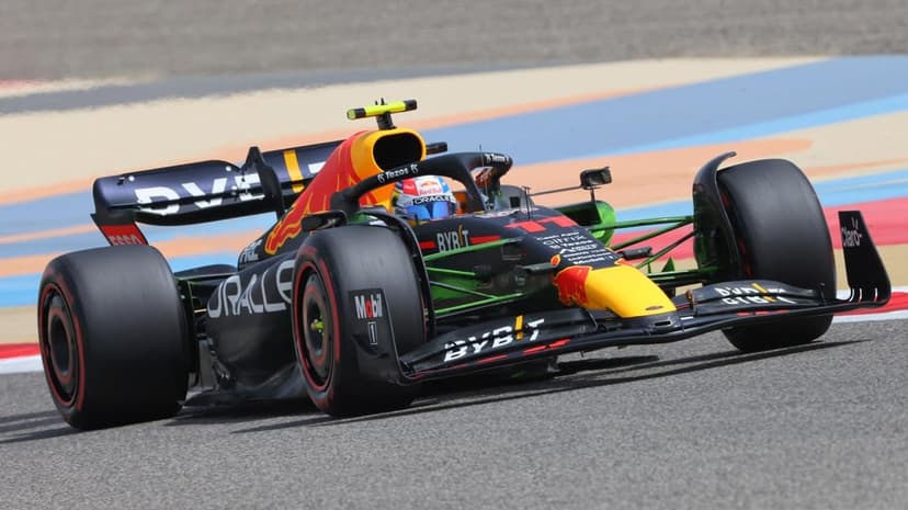 Max Verstappen driving a navy blue Red Bull F1 car with green aerodynamic paint on a colorful race track.