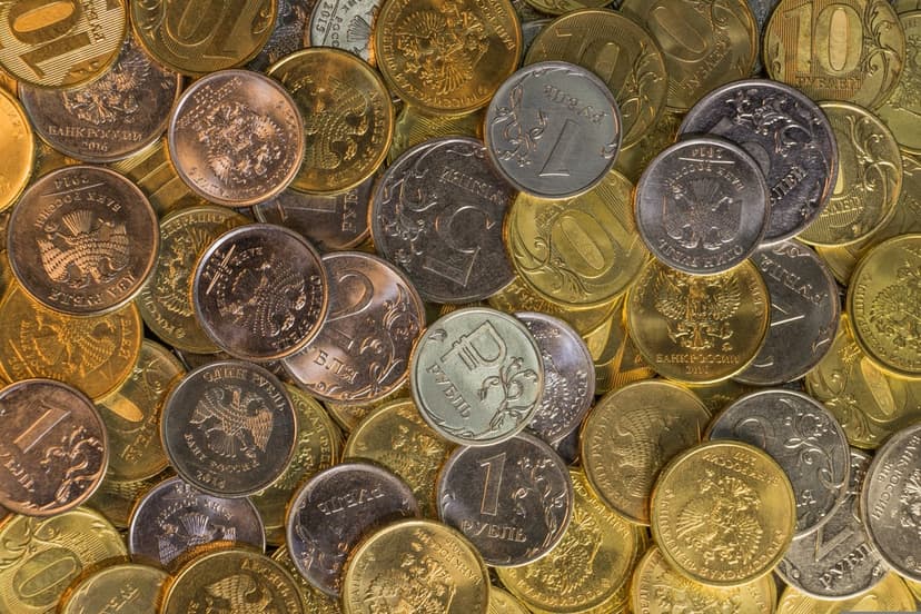 Russian ruble coins in a dense pile showing silver and gold metallic surfaces with engraved national emblems.