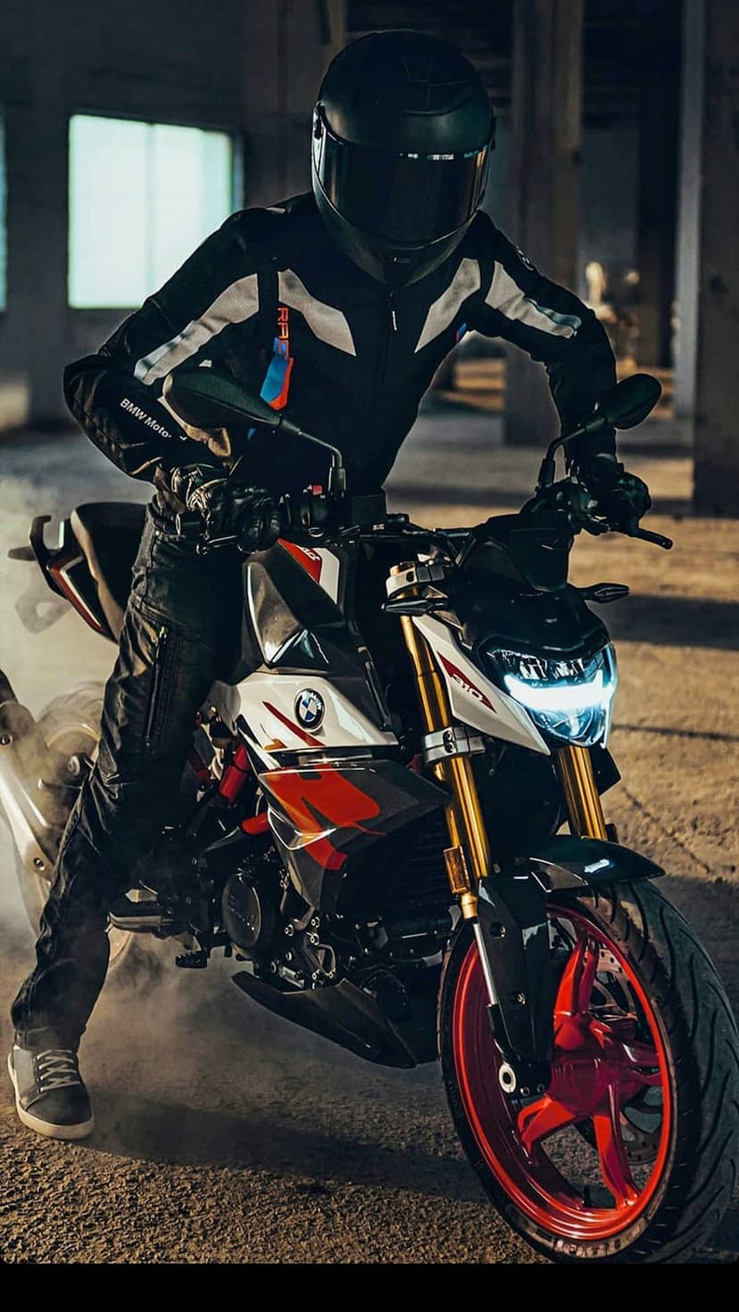 BMW motorcycle rider drifting on a white and red sportbike amid smoke and industrial concrete pillars.