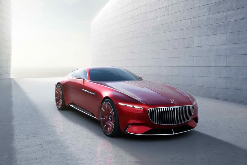 Red Vision Mercedes-Maybach 6 concept car parked near a curved white stone wall in bright outdoor light.
