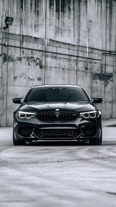 Black BMW M5 parked against a gritty concrete wall
