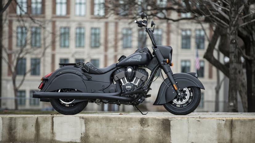 Matte black Indian Chief Dark Horse motorcycle with ape hanger bars parked on a concrete ledge.