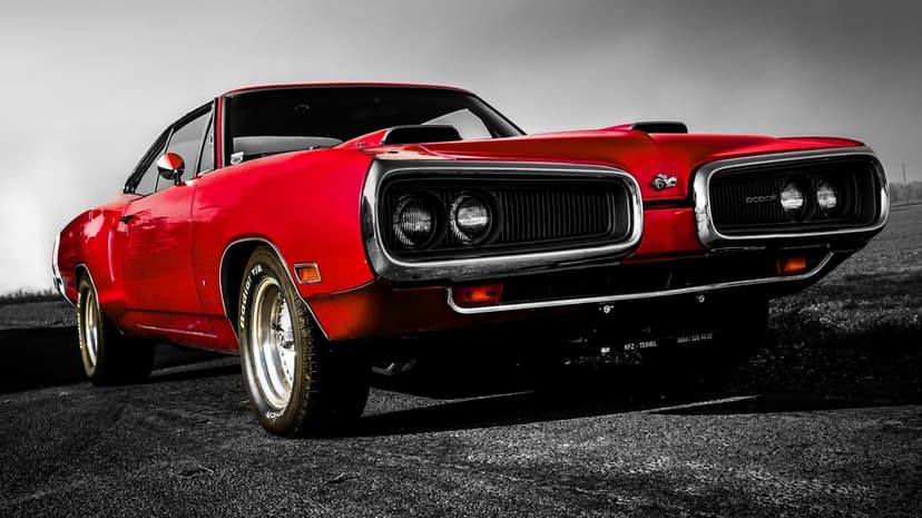 Red 1970 Dodge Coronet Super Bee muscle car with chrome grille and dual hood scoops on a dark asphalt road.