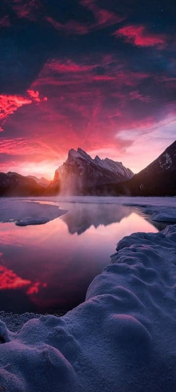 Dramatic Sunset Over Snowy Mountains and Frozen Lake