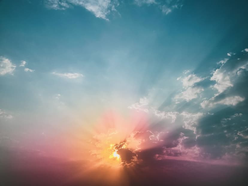 Sunbeams burst through thick orange and dark blue clouds during a dramatic sunset sky in vertical orientation.