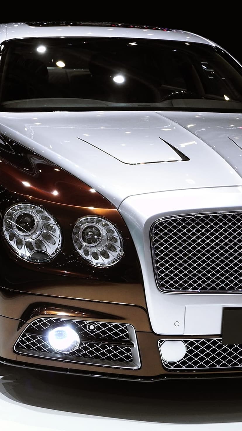 Bentley Continental GT front view featuring a chrome mesh grille, quad headlights, and dual-tone paintwork.