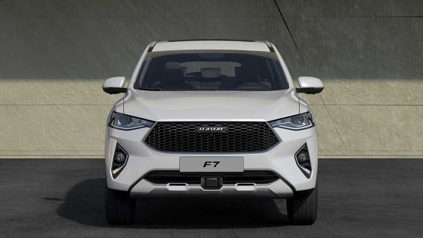 Front view of a white Haval F7 SUV with a black honeycomb grille and LED headlights on a concrete surface.
