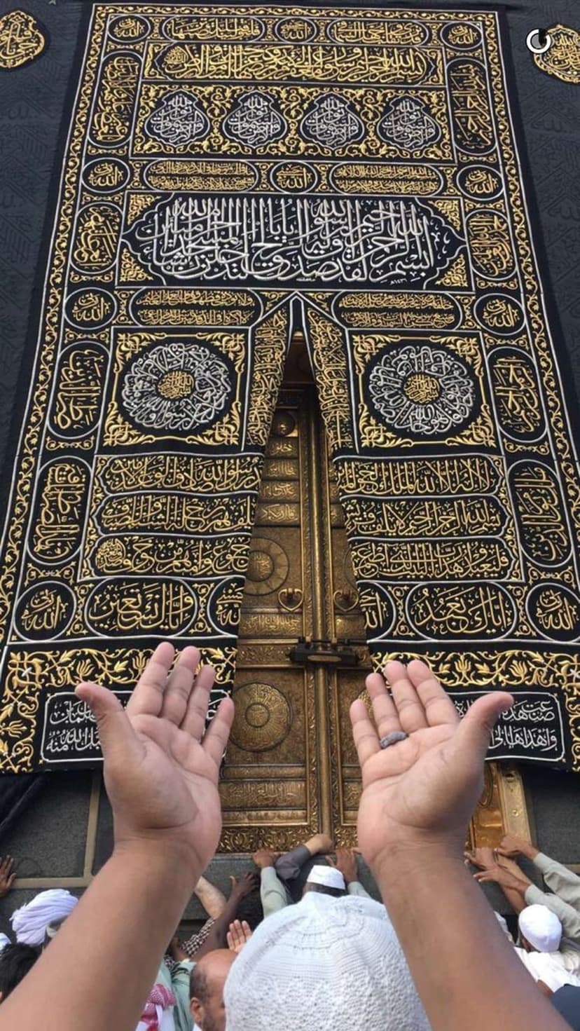 Pilgrims with raised hands pray before the gold-embroidered Kaaba door and black silk Kiswah in Mecca.