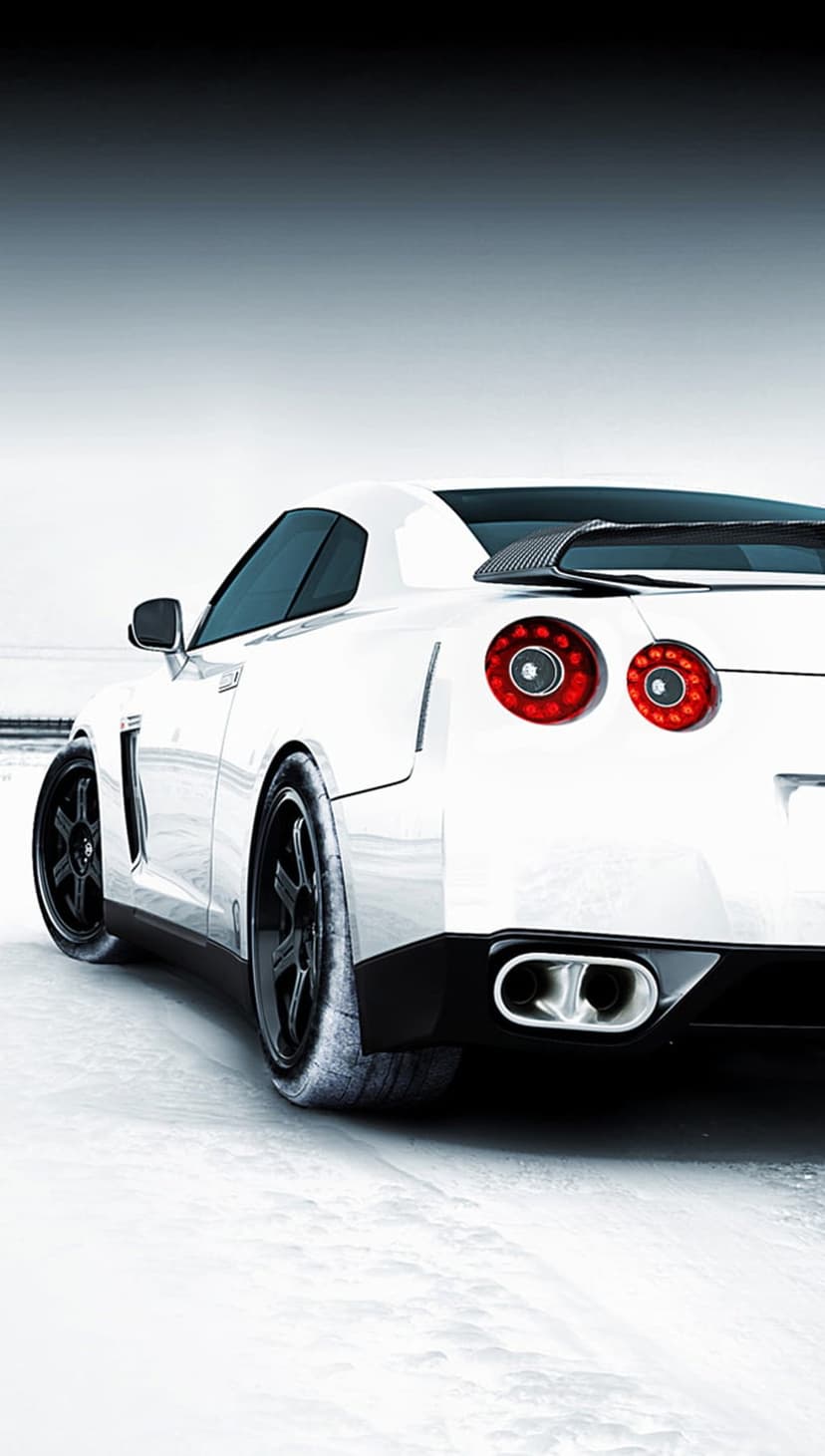 White Nissan GT-R rear view with glowing red circular taillights parked in a deep snowy winter landscape.
