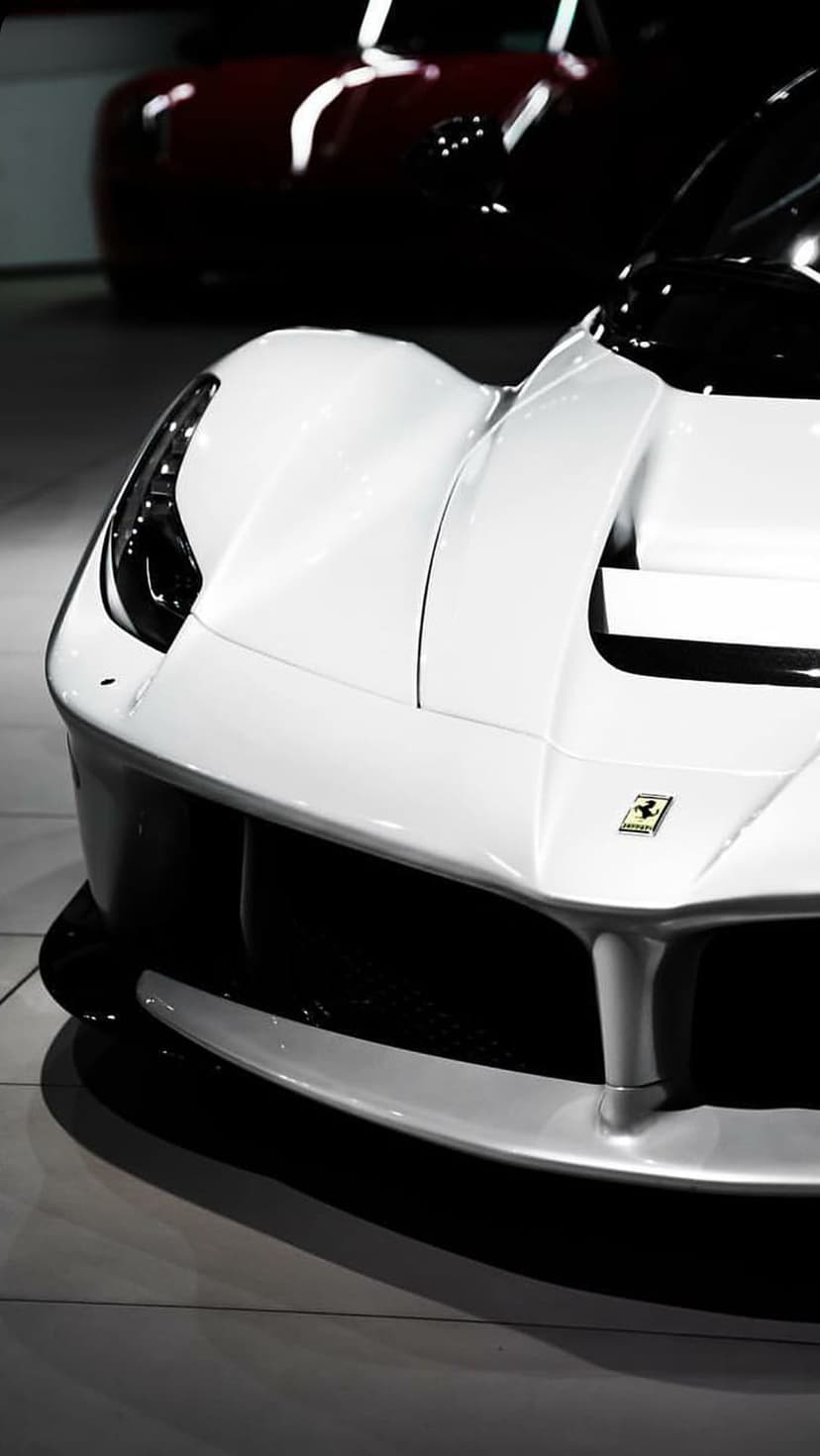 Ferrari LaFerrari front end in white with the Prancing Horse logo, carbon fiber grille, and blurred background.