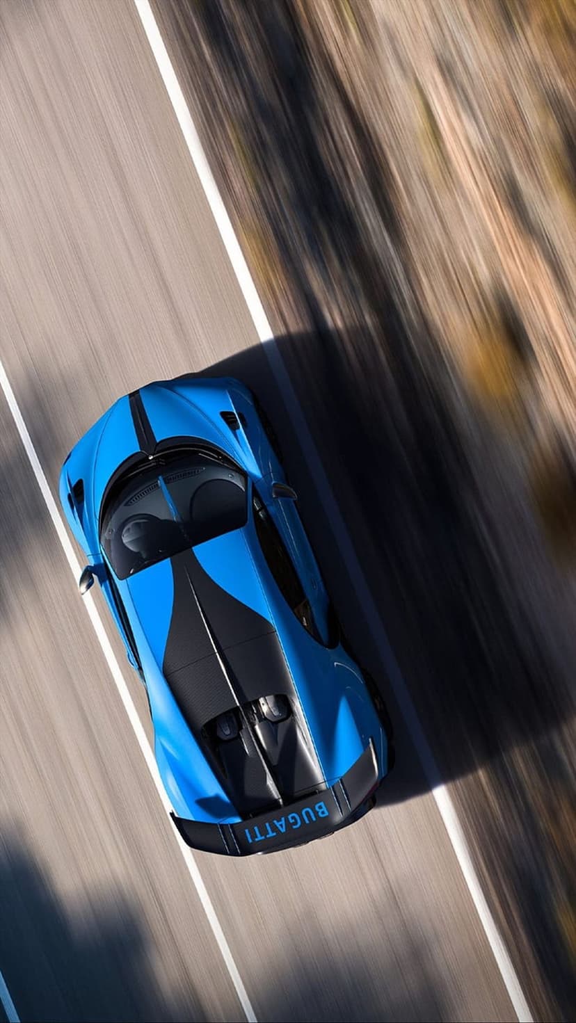 Bugatti Chiron Super Sport 300+ blue hypercar speeds across asphalt from an aerial view with motion blur.