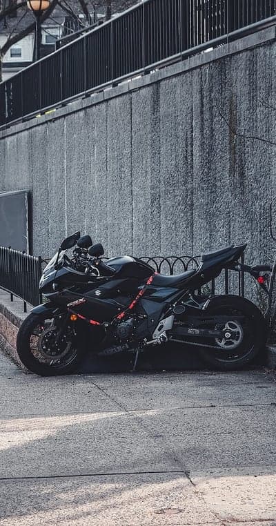 Black Suzuki Motorcycle Parked by Textured Wall