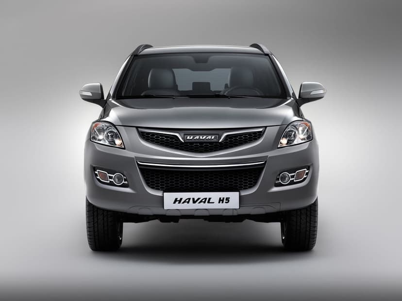Front view of a metallic grey Haval H5 SUV with illuminated headlights in a bright, neutral studio setting.