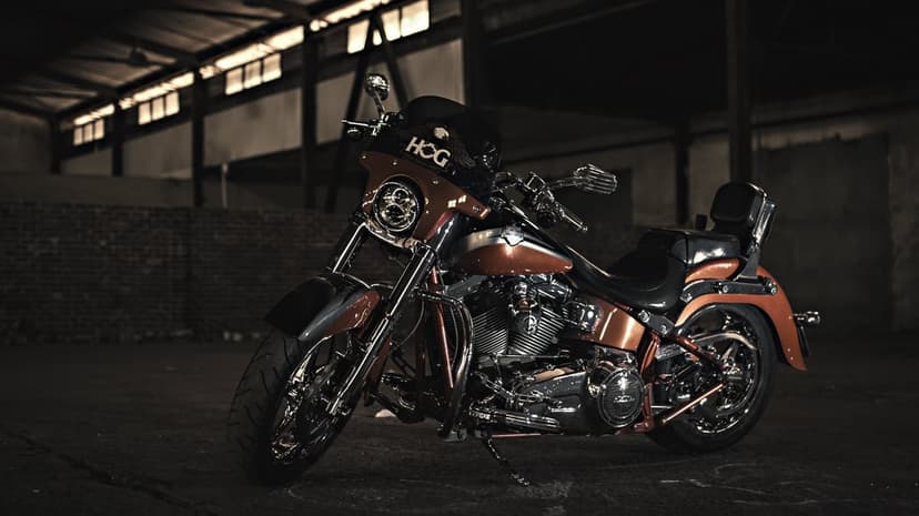 Metallic copper Harley-Davidson motorcycle with chrome accents parked in a dark industrial garage with moody lighting.