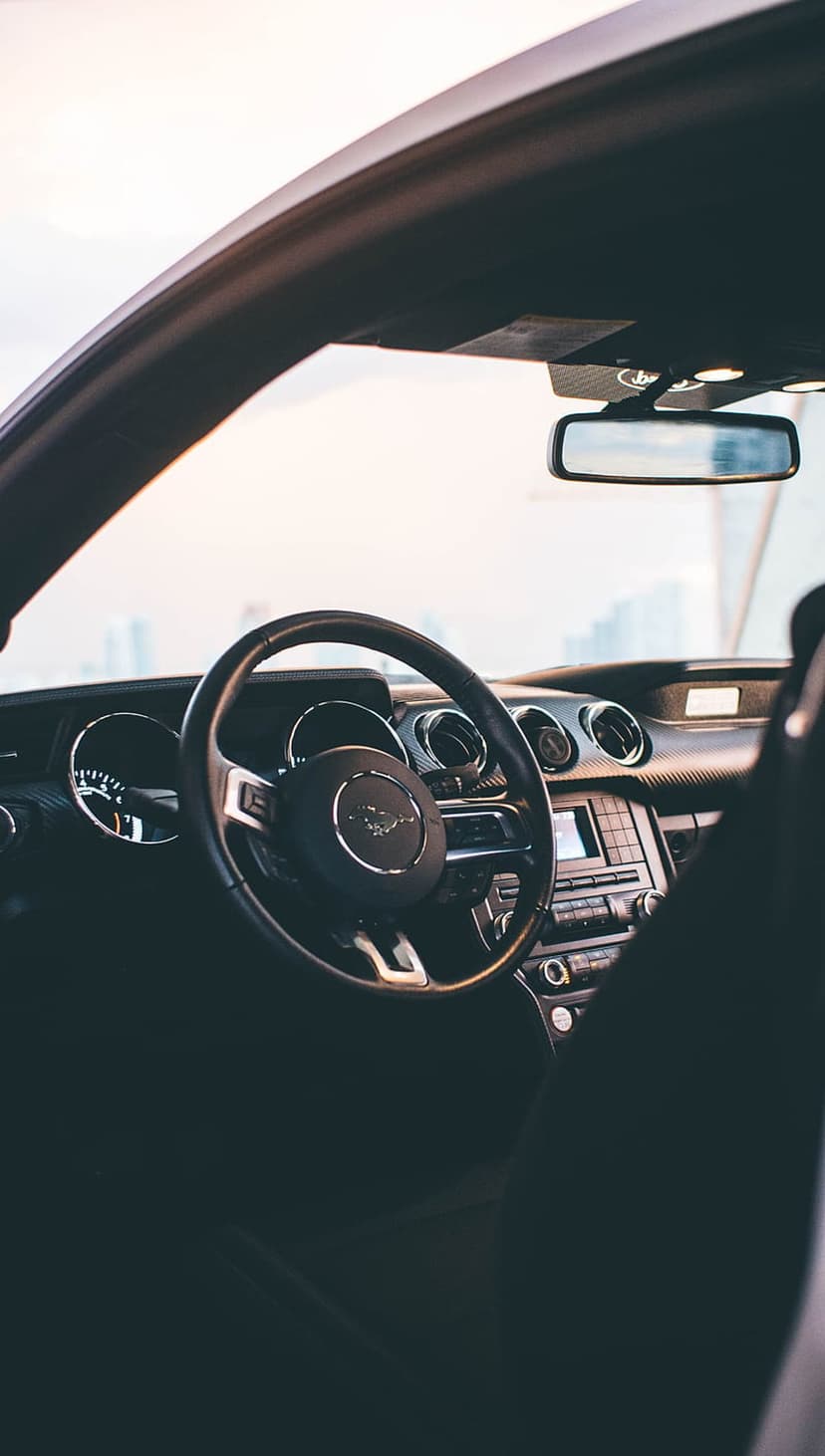 Ford Mustang steering wheel with a pony logo and a modern dashboard featuring circular vents and a touch screen.