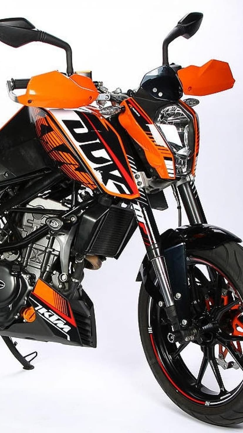 Orange and black KTM Duke motorcycle with handguards shown from a front angle against a white studio background.
