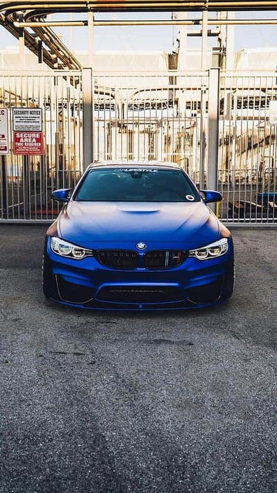 Blue BMW M4 parked at a secure industrial facility