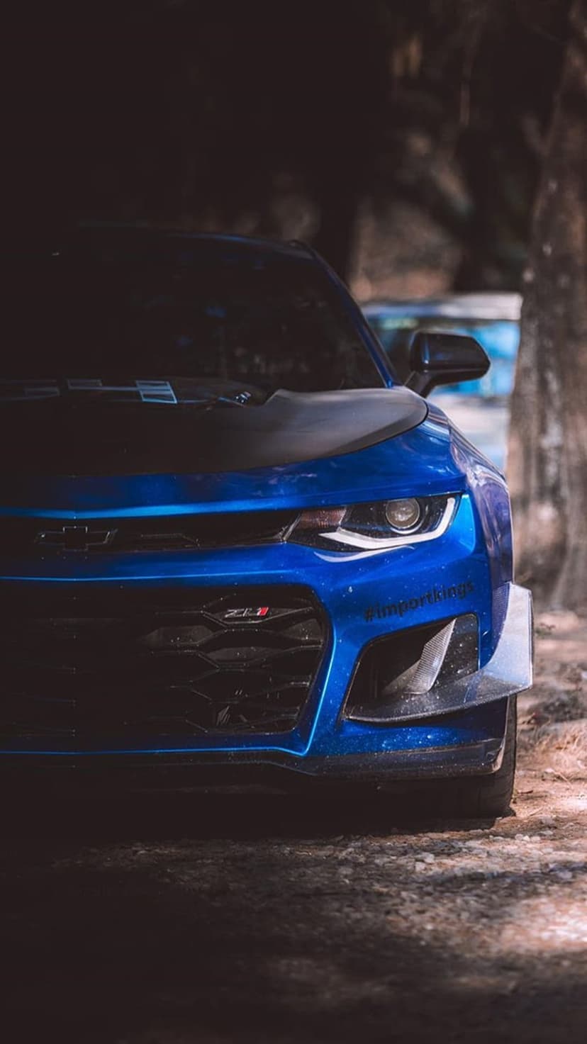 Blue Chevrolet Camaro ZL1 front view features an aggressive black grille and LED headlights from a low perspective.