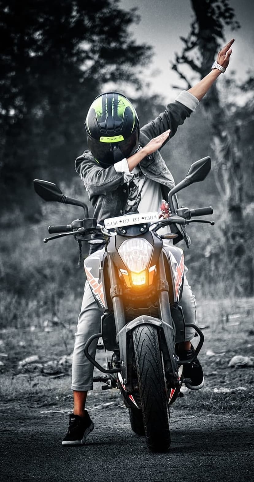 Motorcyclist in a denim jacket poses with arms out on a bike featuring a glowing orange headlight.