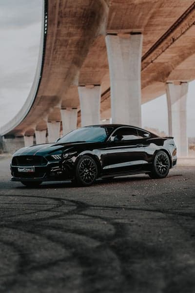 Black Ford Mustang GT under concrete overpass